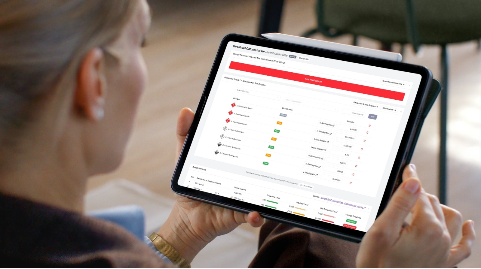 OHS consultant reviewing dangerous goods compliance software on a tablet showing threshold calculator and site inventory